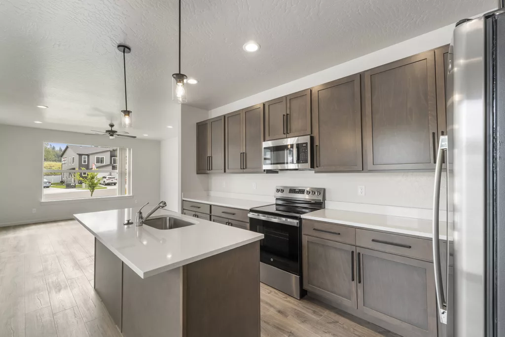 Modern kitchen with stainless steel appliances, white countertops, dark wood cabinets, and a center island with a sink.