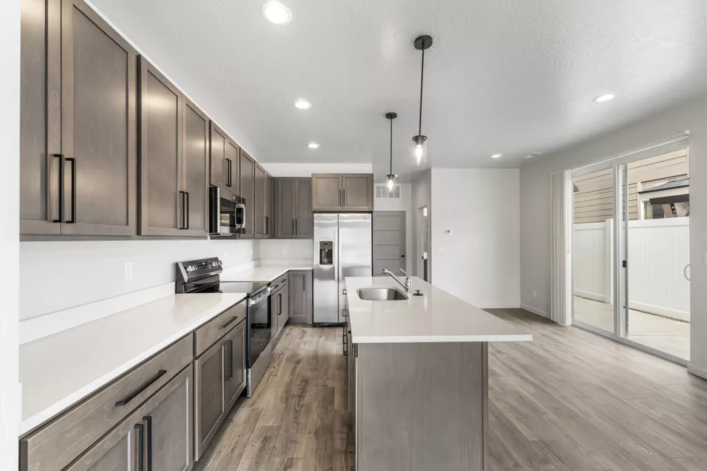 Modern kitchen with dark wood cabinets, stainless steel appliances, a kitchen island with sink, and sliding patio doors.