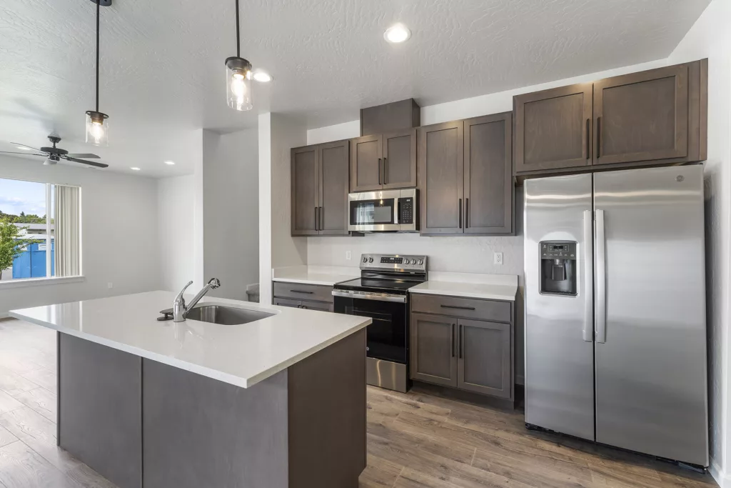 Modern kitchen with stainless steel appliances, dark wood cabinets, and a central island with a sink.