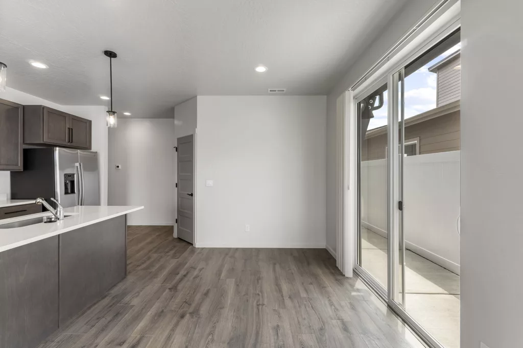 A modern kitchen with dark cabinets, a light countertop, and sliding glass doors leading to an outdoor area.