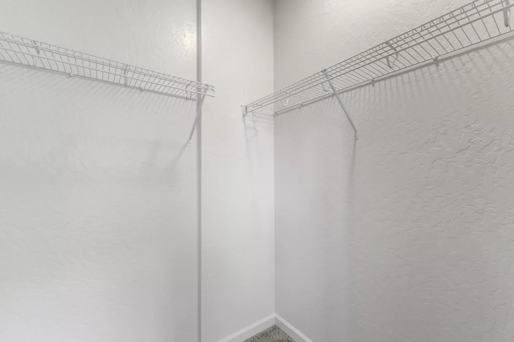 Empty white closet with wire shelving on two walls.